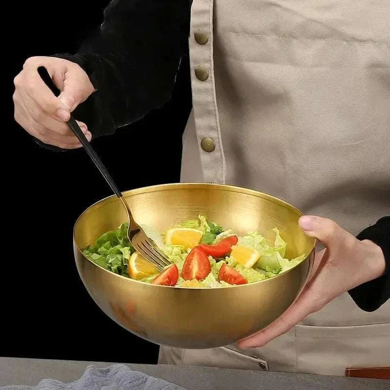 Stainless steel gold salad bowl with vegetables and fork.