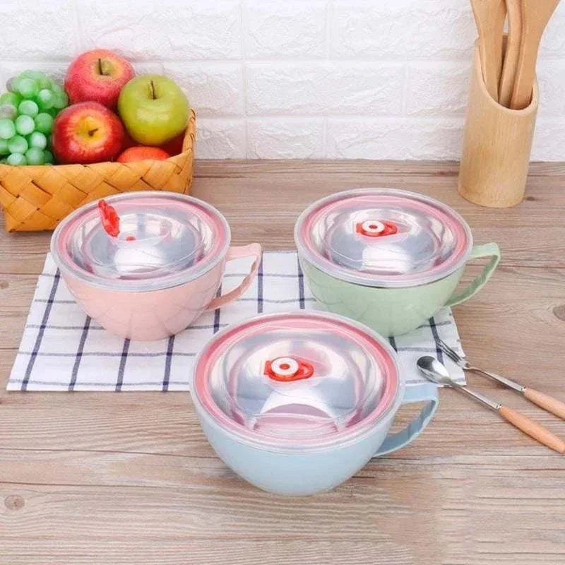 Stainless steel bowls with handles in pink, green, and blue on a kitchen table.