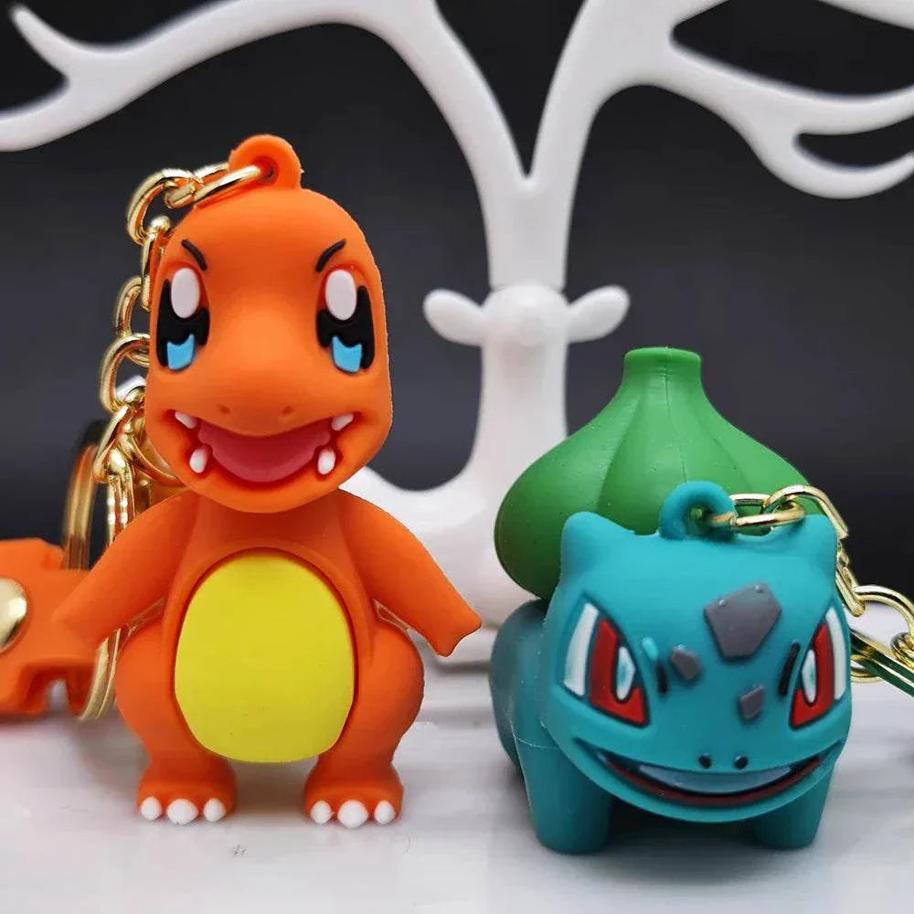 Two Pokemon keychains featuring a cheerful orange character and a blue-green character with a leafy back, both attached to golden lobster clasp chains.