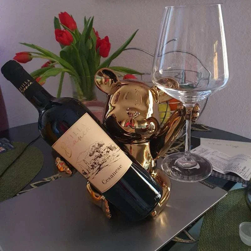 Ceramic bear wine rack cup holder with wine bottle and glass on table, home decoration.